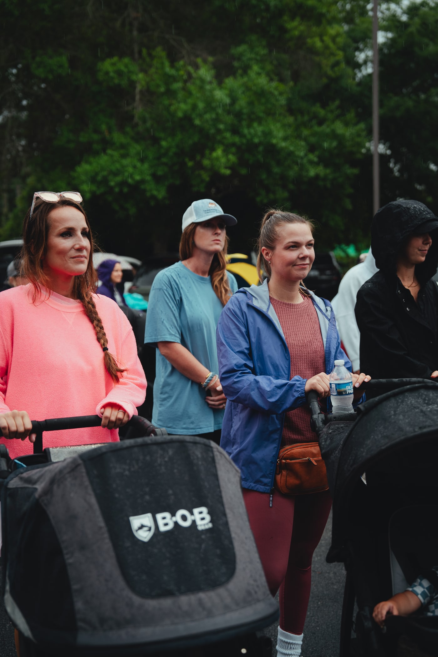 A small group of moms with strollers, listening at Babes & Barbells